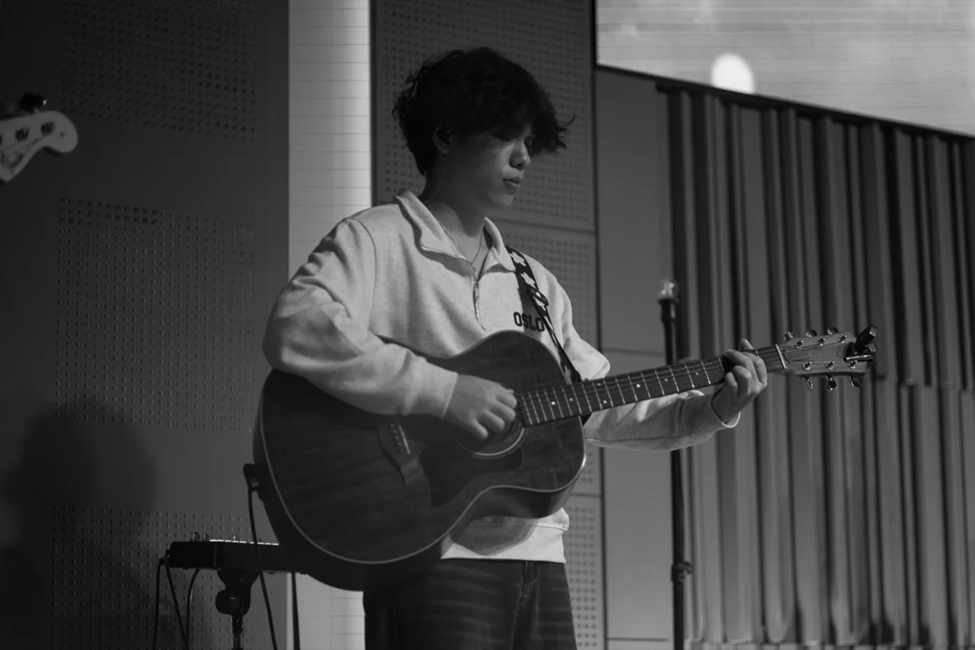 A teenage boy playing acoustic guitar on stage